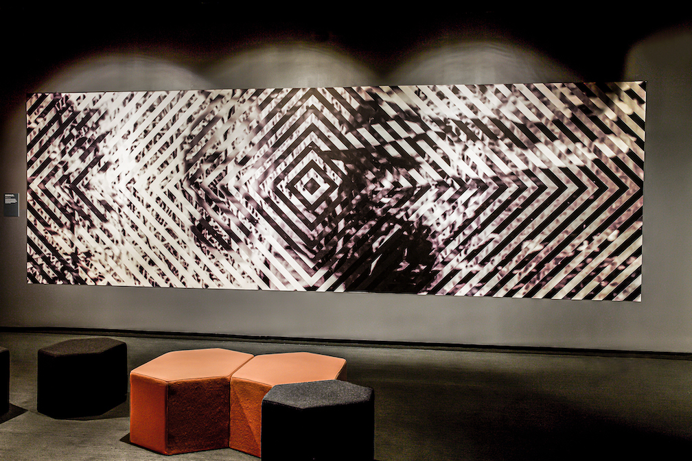 A large-scale, black and white graphic of concentric squares printed on vinyl and adhered to the wall in the gallery where the film "From My Home to Yours" is being screened.