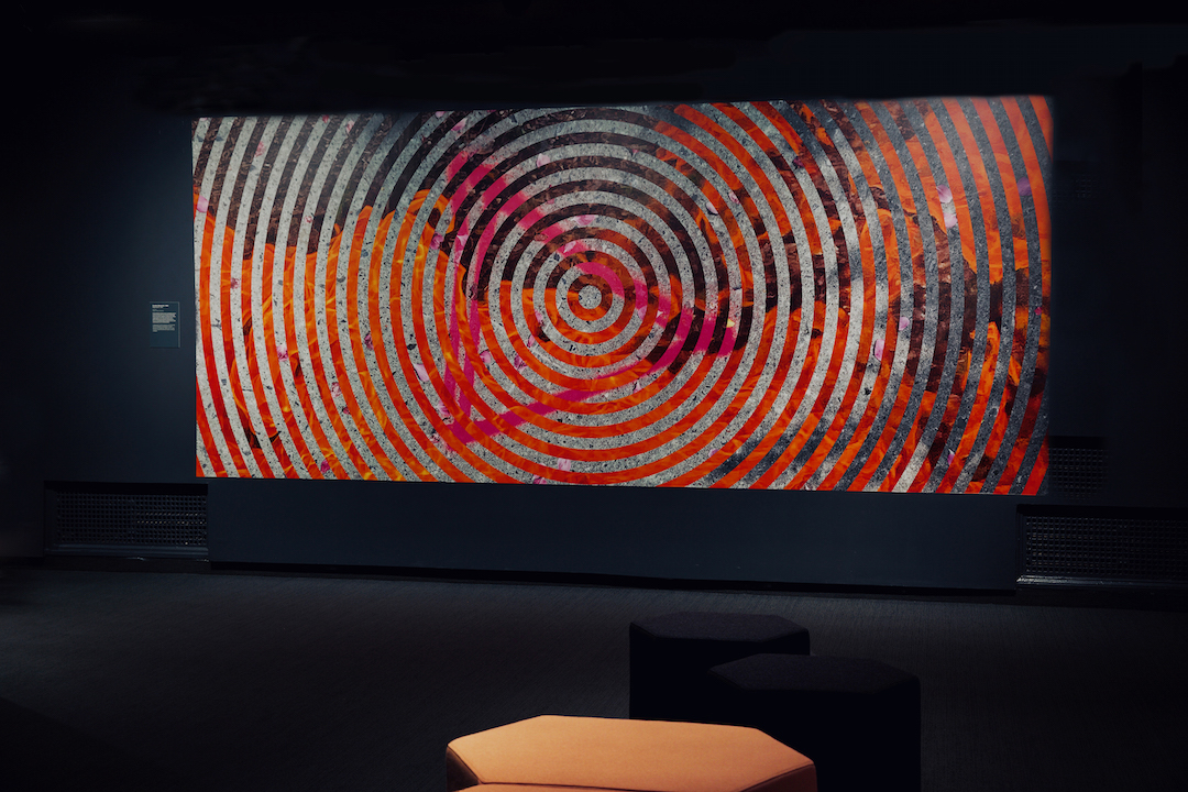 A large-scale, colorful graphic of concentric circles printed on vinyl and adhered to the wall in the gallery where the film "From My Home to Yours" is being screened.