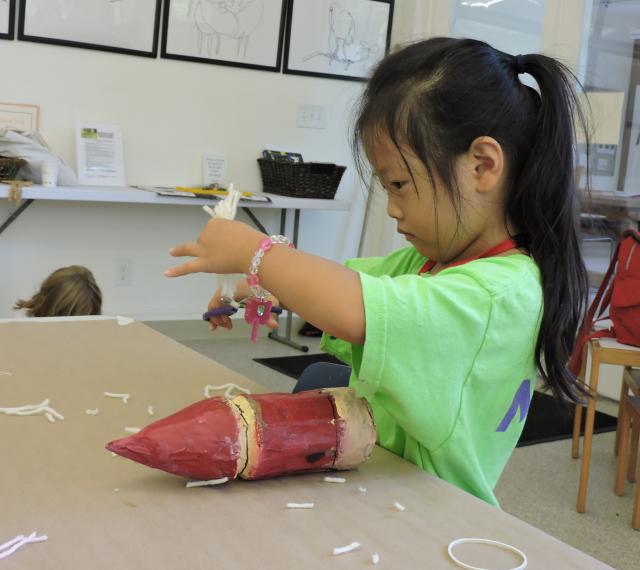 A young camper is cutting out tape to use in an art project. 