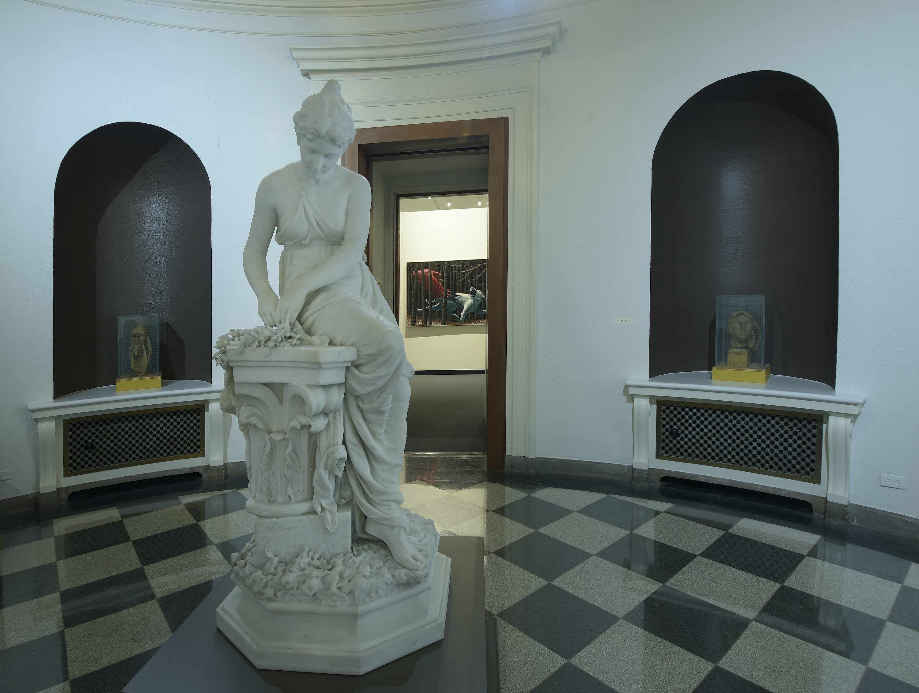 A view of the rotunda gallery, a small round room with a marble statue of a woman in the middle. Alcoves on either side of the statue have artworks in them as well.