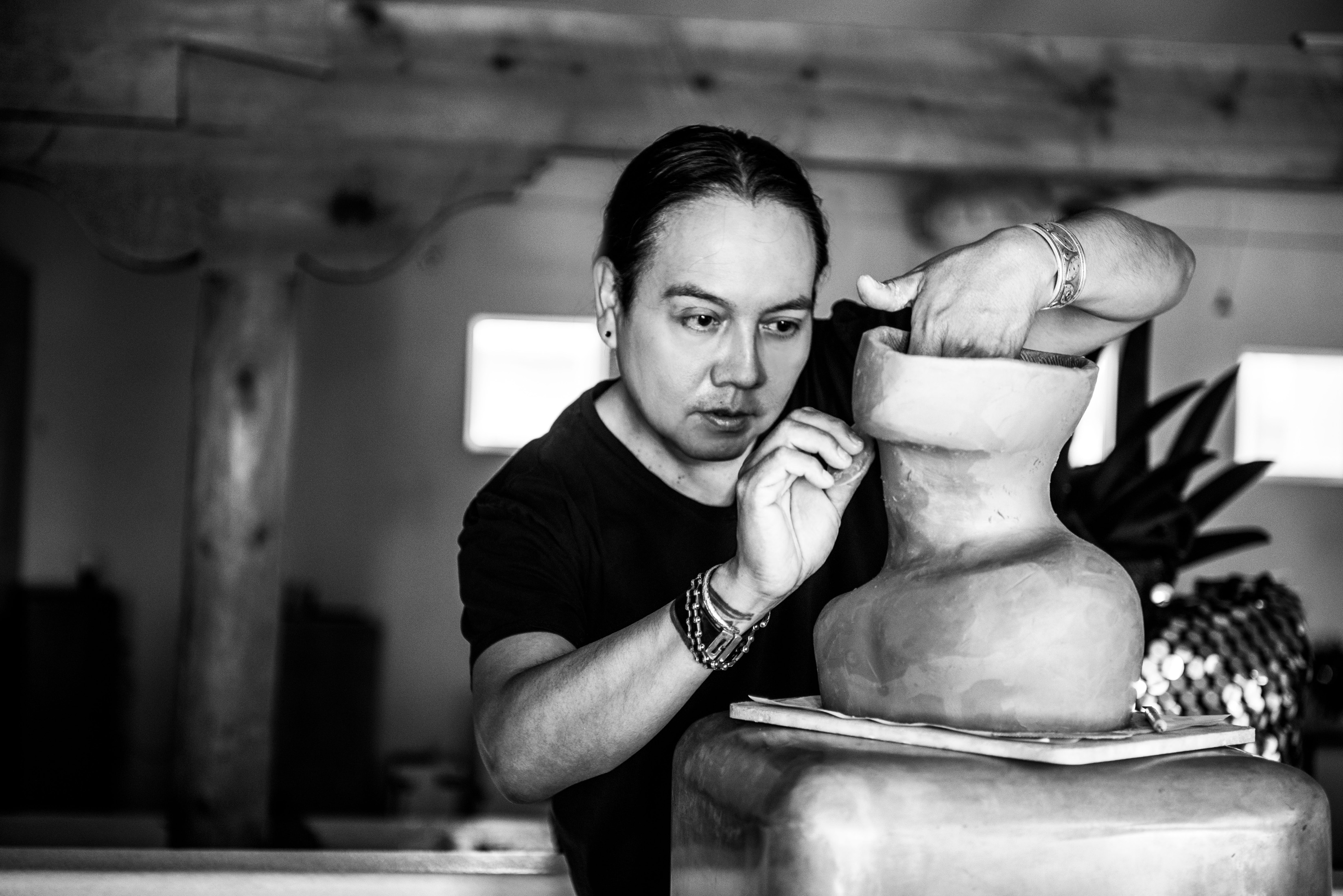 I'm an image! Virgil Ortiz sculpting clay by hand in his studio. Ortiz is focused on his work and not looking at the camera.