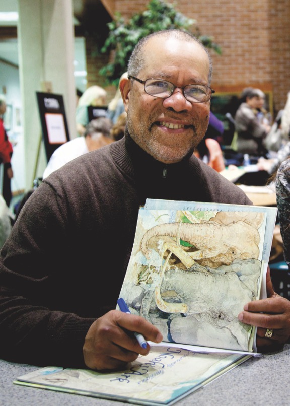 Jerry Pinkney pausing to smile for the camera while signing a book.