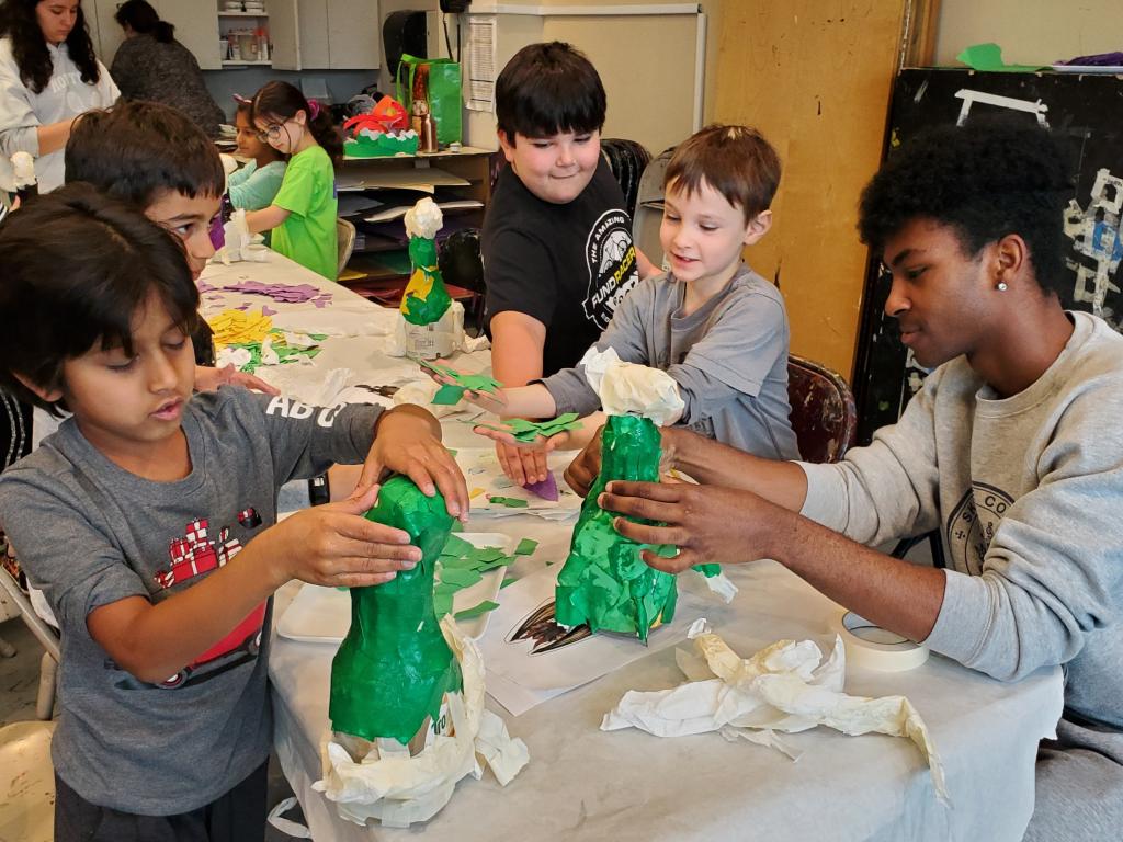 young students are working on papier mache projects at a table.