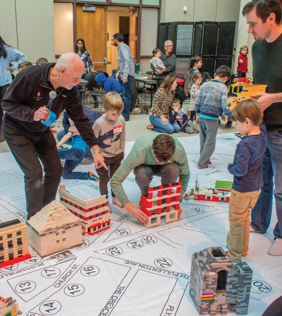 Children and adults placing their finished LEGO constructions on a giant floor map of Montclair, NJ during MAM's Building Montclair in LEGO event.
