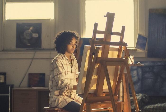 I'm an image! a woman is painting on an easel in a home studio. She is focused on her art and is not looking at the camera.