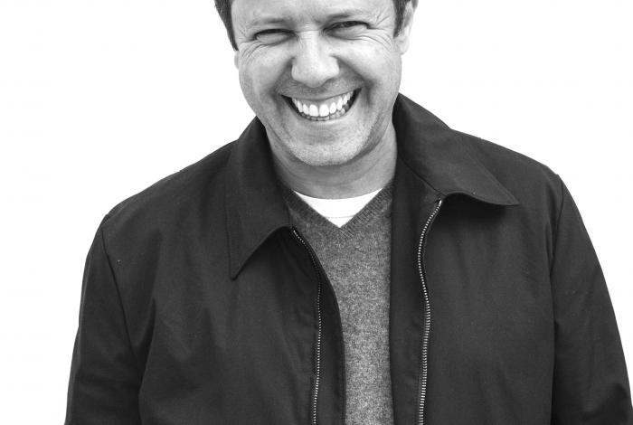 A black and white photo portrait of Vik Muniz laughing