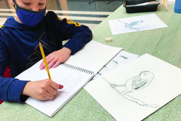 A student is drawing in a sketchbook